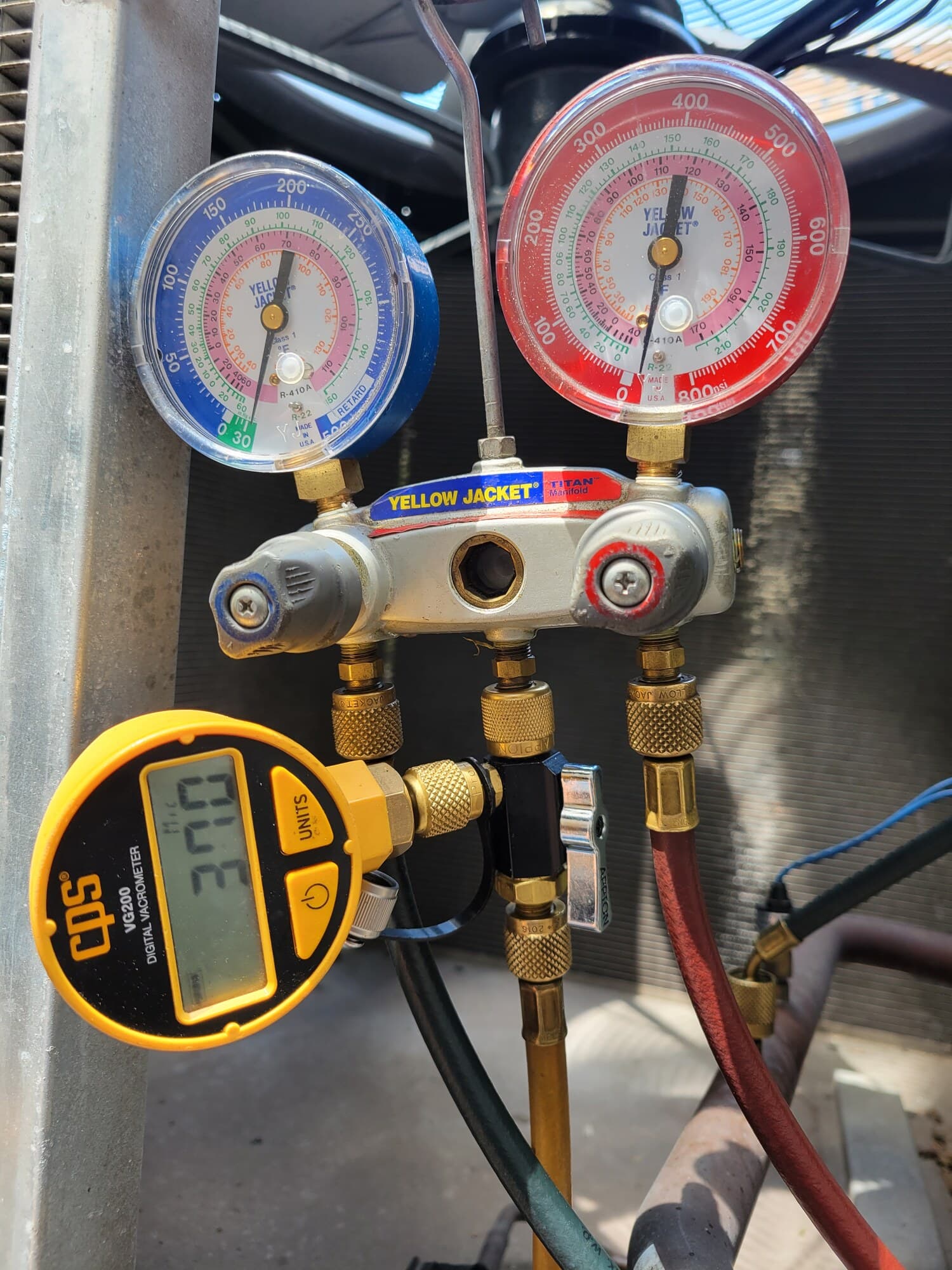 Refrigerant manifold gauges and digital micron gauge connected during a chiller diagnostic.