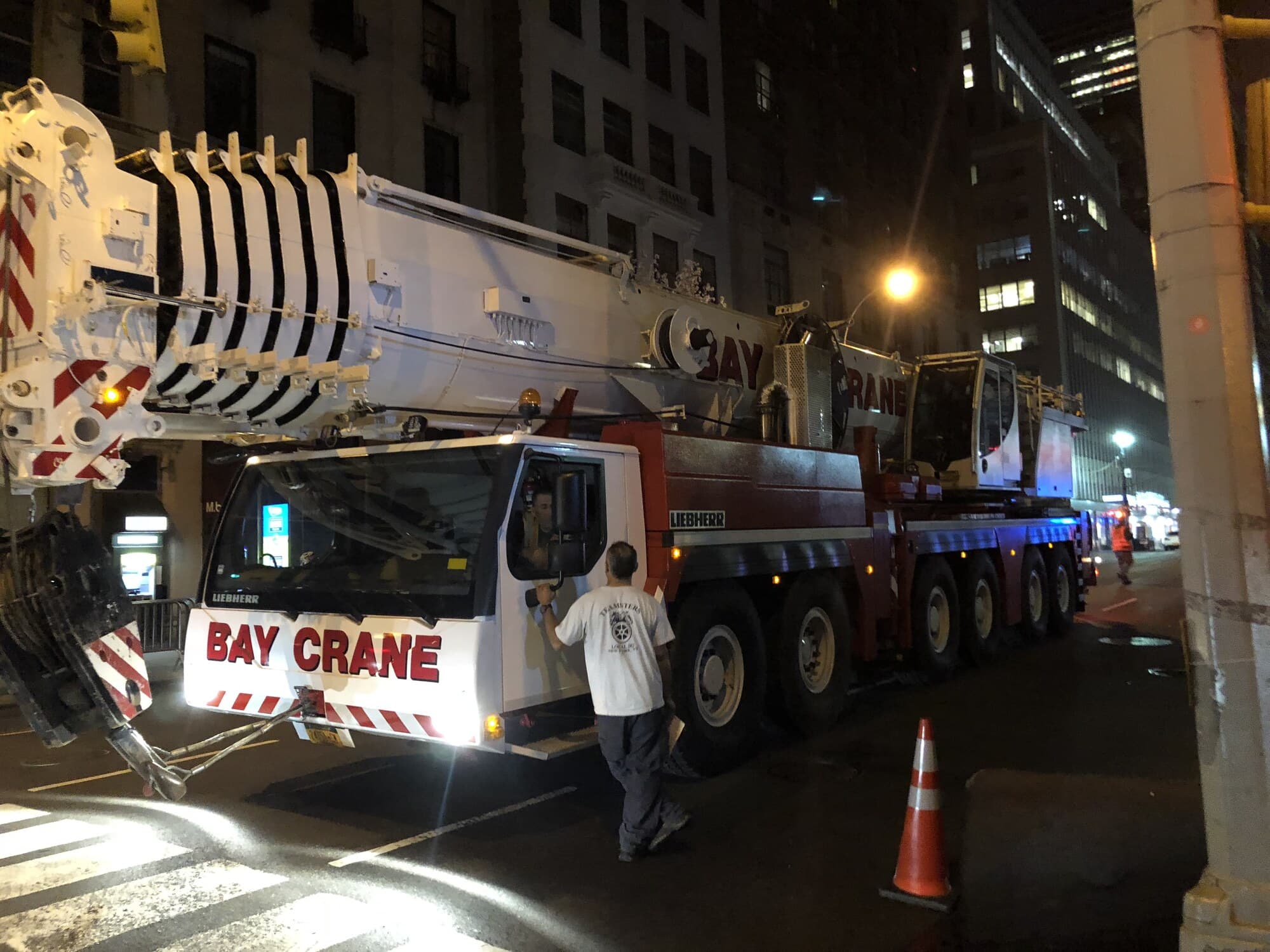Bay Crane Liebherr all-terrain crane staged at night on Madison Avenue with the operator in the cab