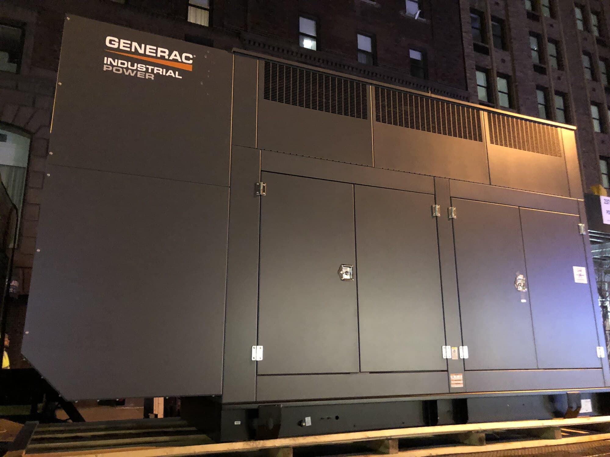 Generac industrial generator staged at night in front of a luxury apartment building at Madison and 37th
