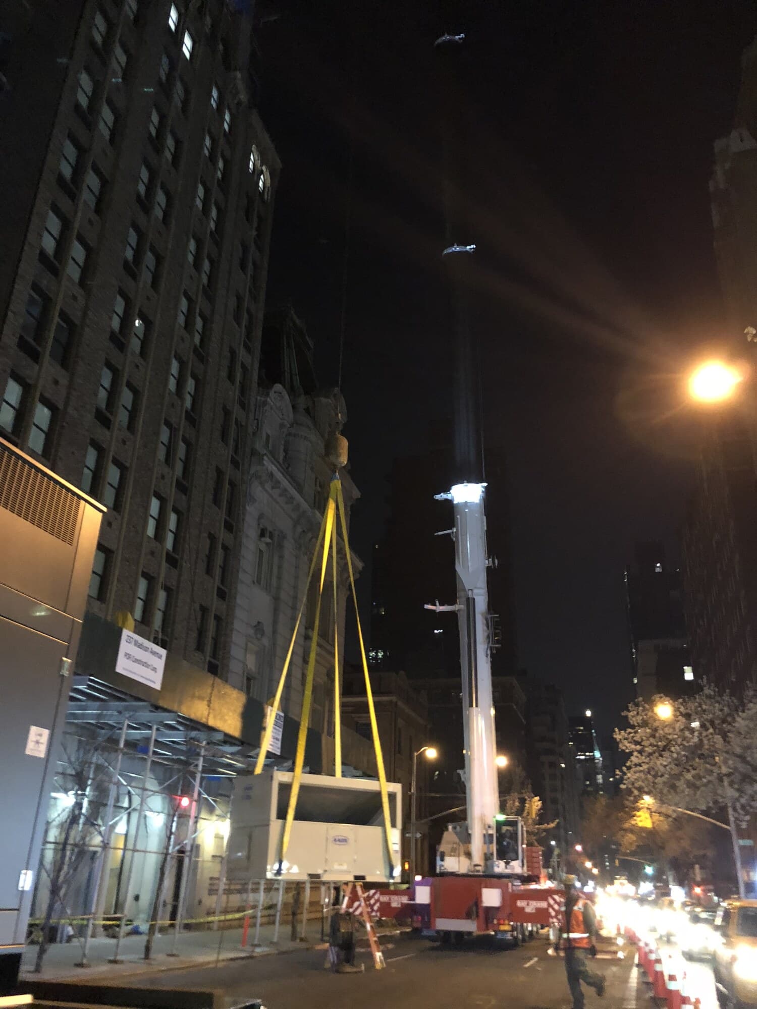 Yellow rigging straps set on a 30-ton AAON rooftop unit at street level on Madison Avenue at night