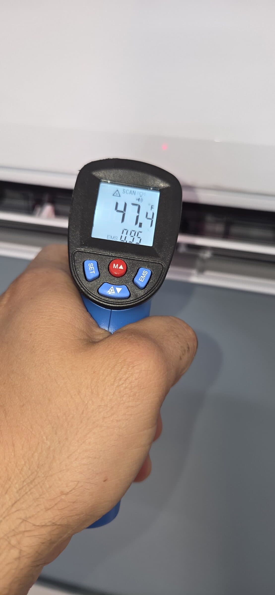 Infrared thermometer reading 47.4 degrees Fahrenheit at a wall-mounted indoor head during commissioning