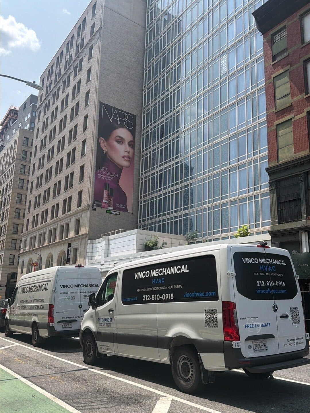 White Vinco Mechanical Mercedes eSprinter electric van, rear badge with QR code and vincohvac.com, parked off Lafayette Street in SoHo below a glass tower