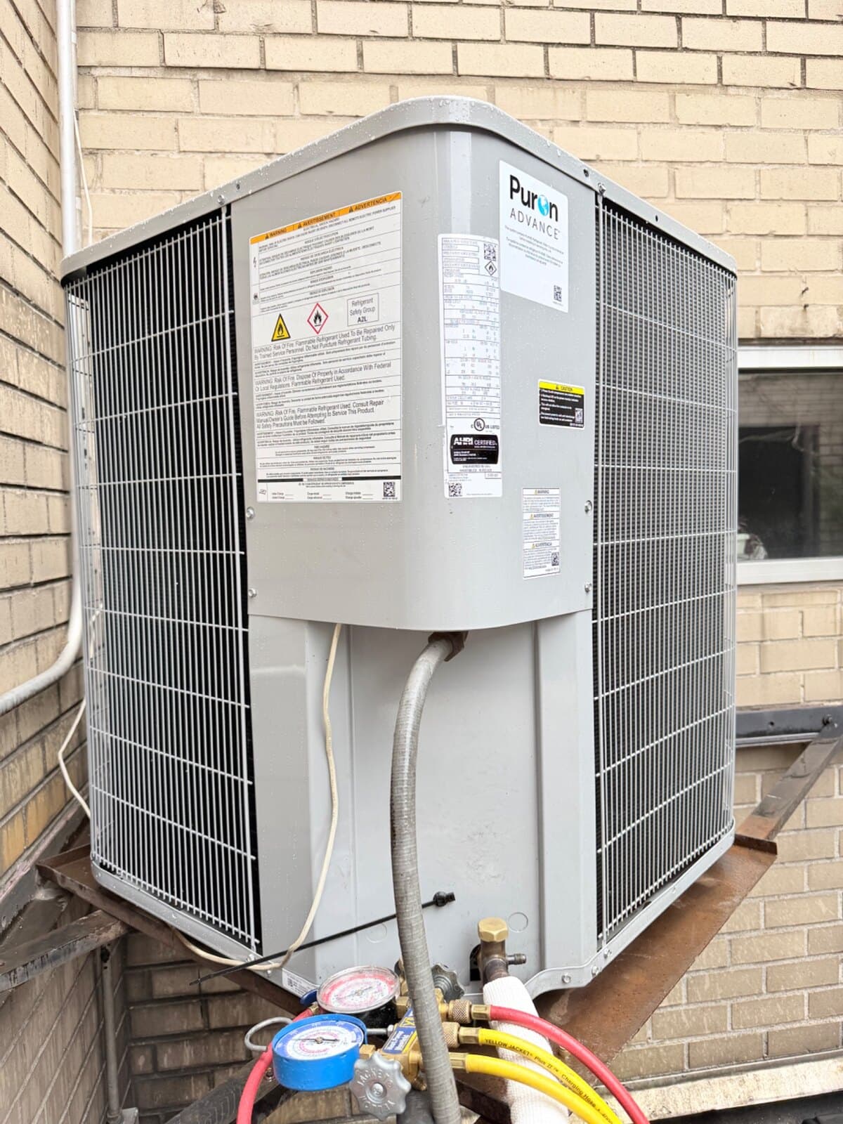 Carrier Puron Advance R-454B condenser during commissioning at an Upper East Side co-op, gauge manifold connected, A2L safety label visible