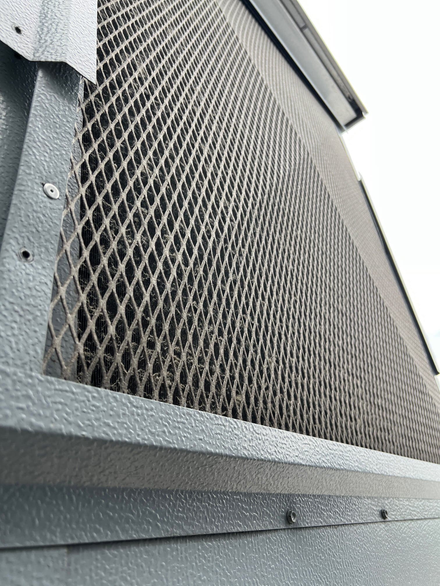 Dust-loaded rooftop condenser coil guard at a Red Hook building before cleaning