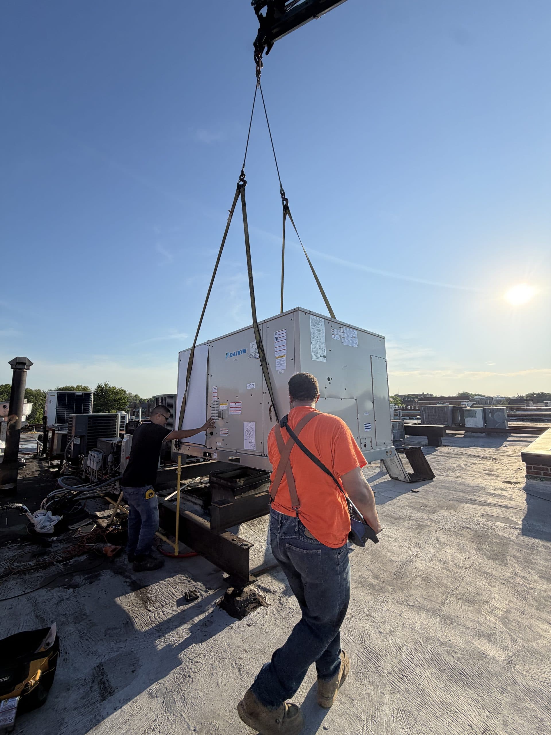 Vinco Mechanical crew rigging a rooftop unit into place with a crane on a Brooklyn roof