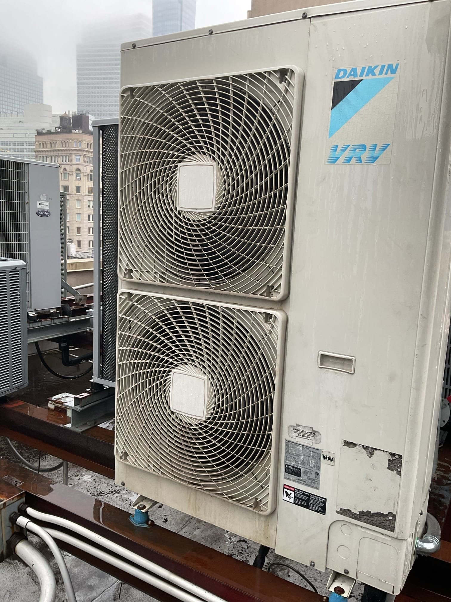 Daikin VRV condensing unit on a Tribeca rooftop with Lower Manhattan towers in fog behind it