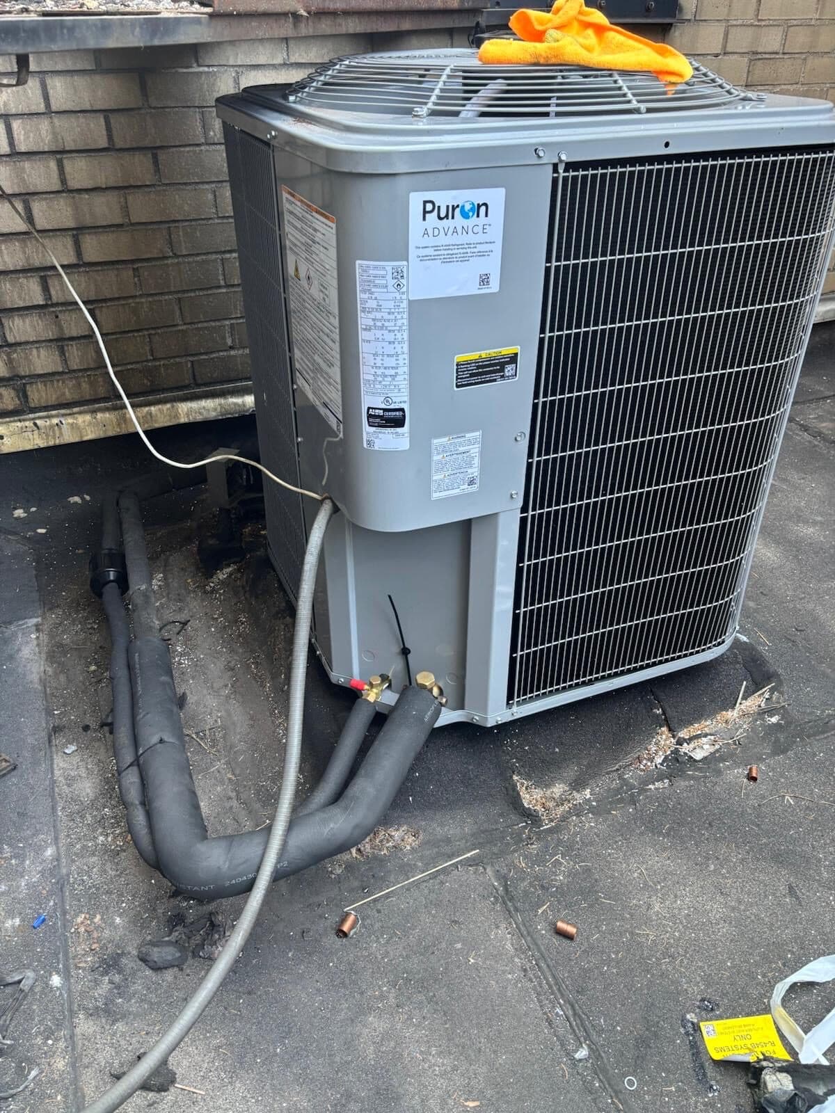 Carrier Puron Advance R-454B condenser on an Upper East Side co-op rooftop, insulated linesets and service valves, R-454B flammable-refrigerant label on the deck